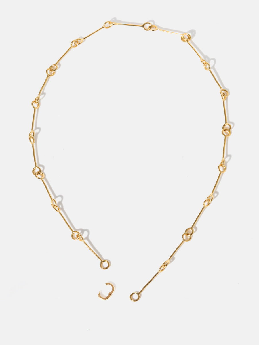 A gold 18 inch link chain necklace undone at the bottom with the clicker connector open to illustrate how it connects