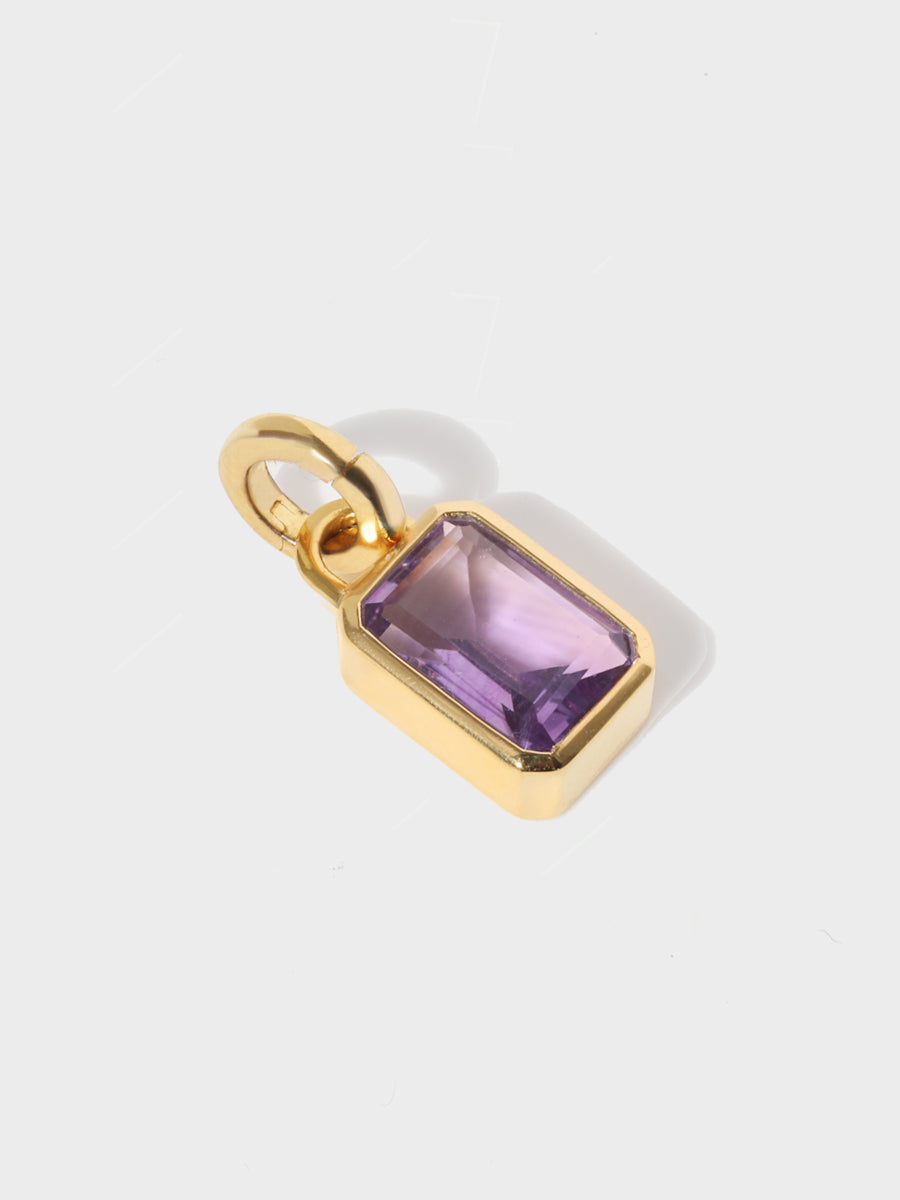 A large Brazilian amethyst baguette shaped charm set in a gold casing with large connection hoop at the top and clicker connector attahced. Grey background with shadow