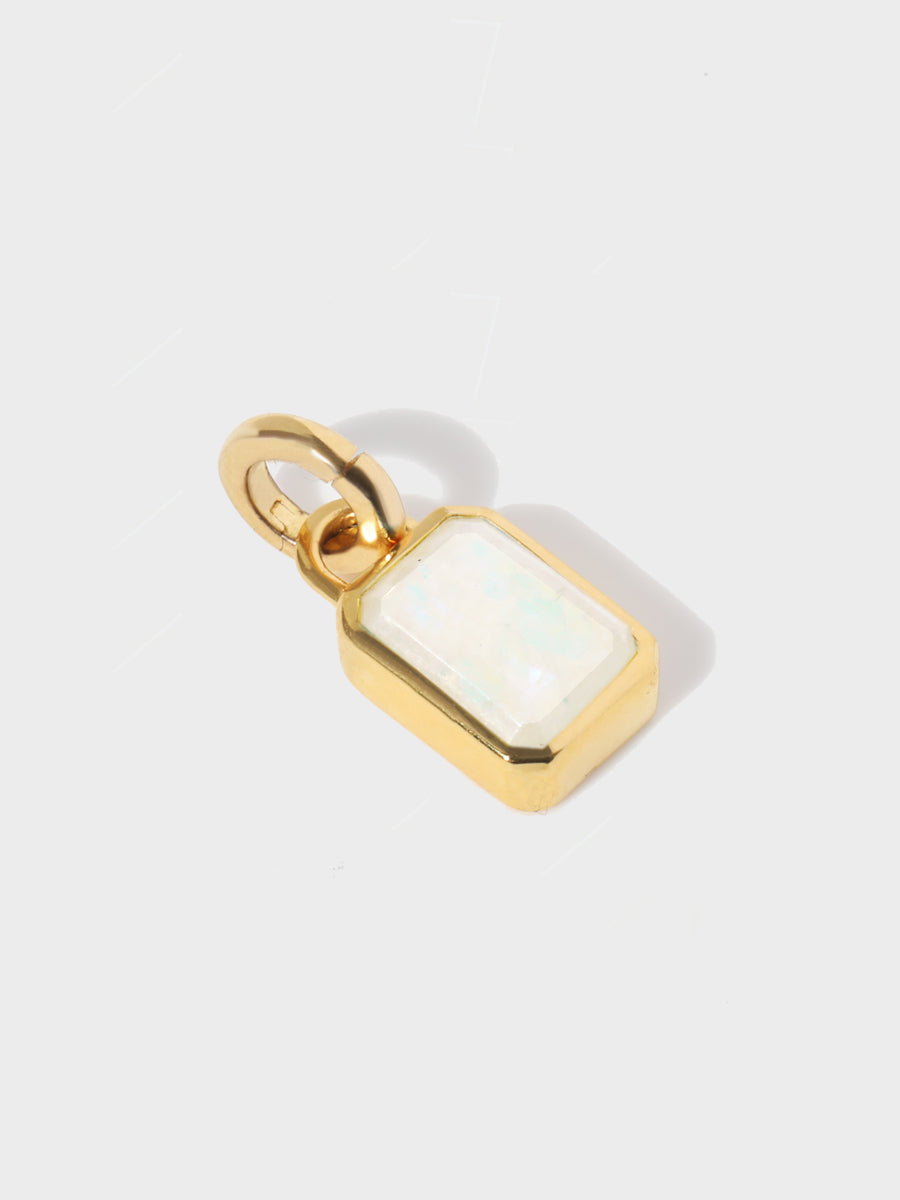 A large moonstone baguette shaped charm set in a gold casing with large connection hoop at the top and clicker connector attahced. Grey background with shadow