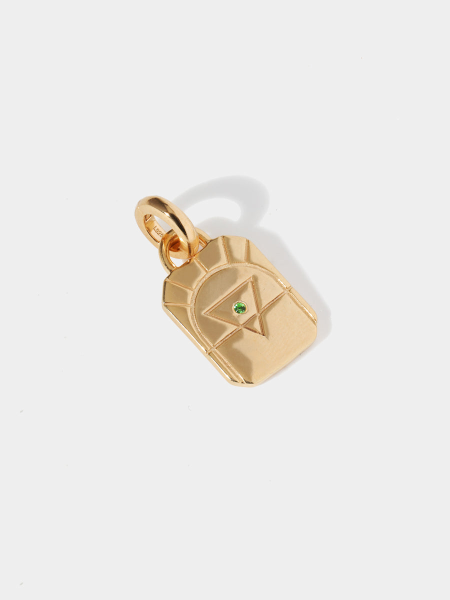 A gold earth element rectangular charm with chamfered corners and a central green emerald and large connection hoop at the top and clicker connector attached. Grey background with shadow
