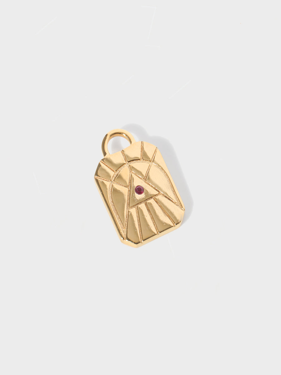 A gold fire element rectangular charm with chamfered corners and a central ruby and large connection hoop at the top. Grey background with shadow