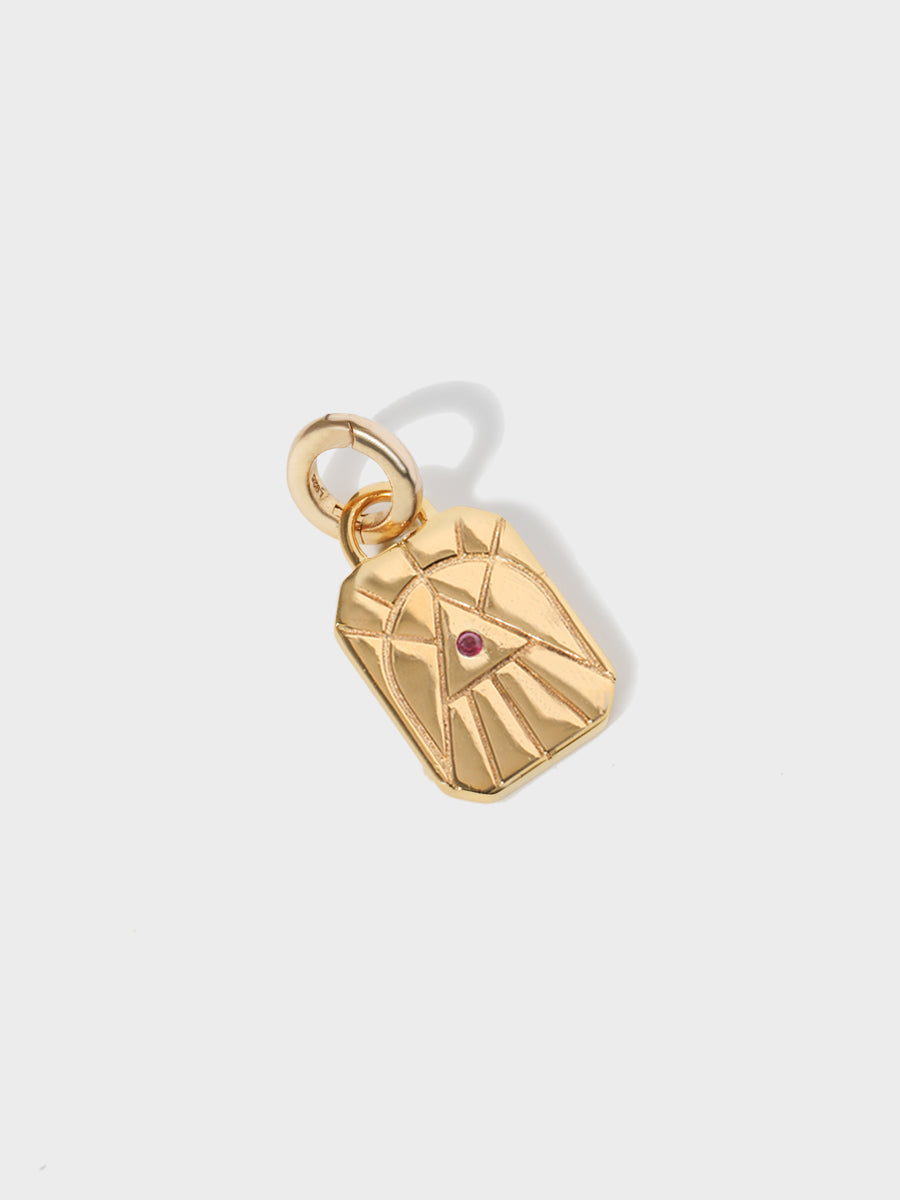 A gold fire element rectangular charm with chamfered corners and a central ruby and large connection hoop at the top and clicker connector attached. Grey background with shadow
