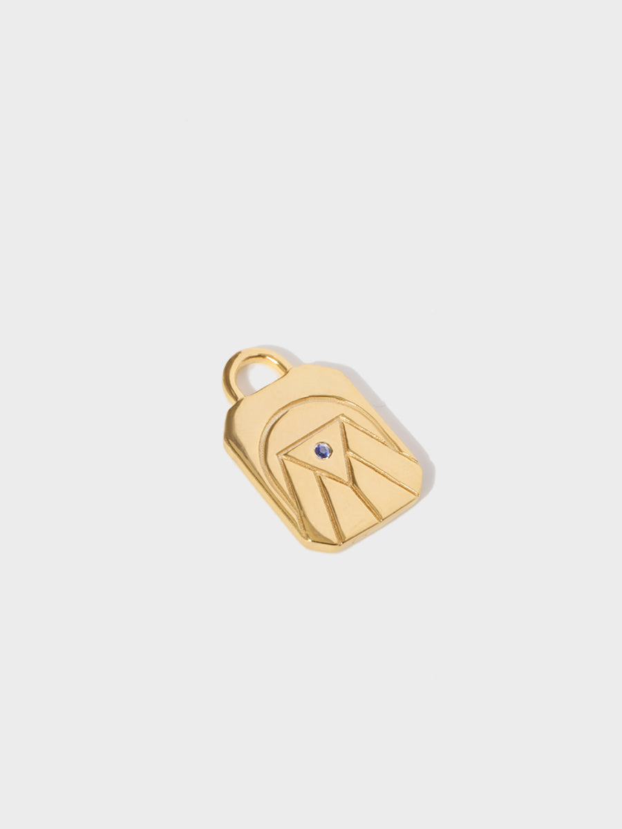 A gold water element rectangular charm with chamfered corners and a central blue sapphire and large connection hoop at the top. Grey background with shadow