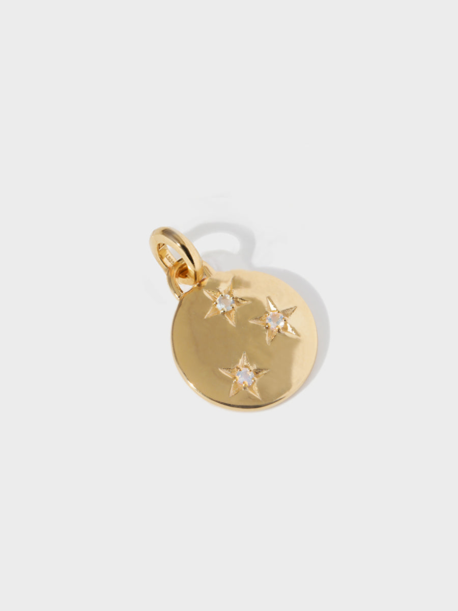 A gold circular necklace pendant set with 3 moonstone gemstones in star cutouts with a large hoop at the top and clicker connector attached. Grey background with shadow.