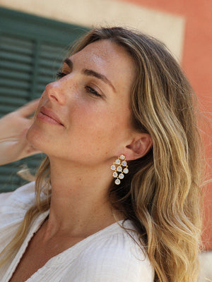 Woman wearing a pair of gold cascading moonstone gemstone cocktail earrings in natural light