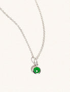 A sterling silver delicate chain nacklace with an 8mm emerald quartz gemstone set in a round pendant. Set on an cream background with gentle shadowing.