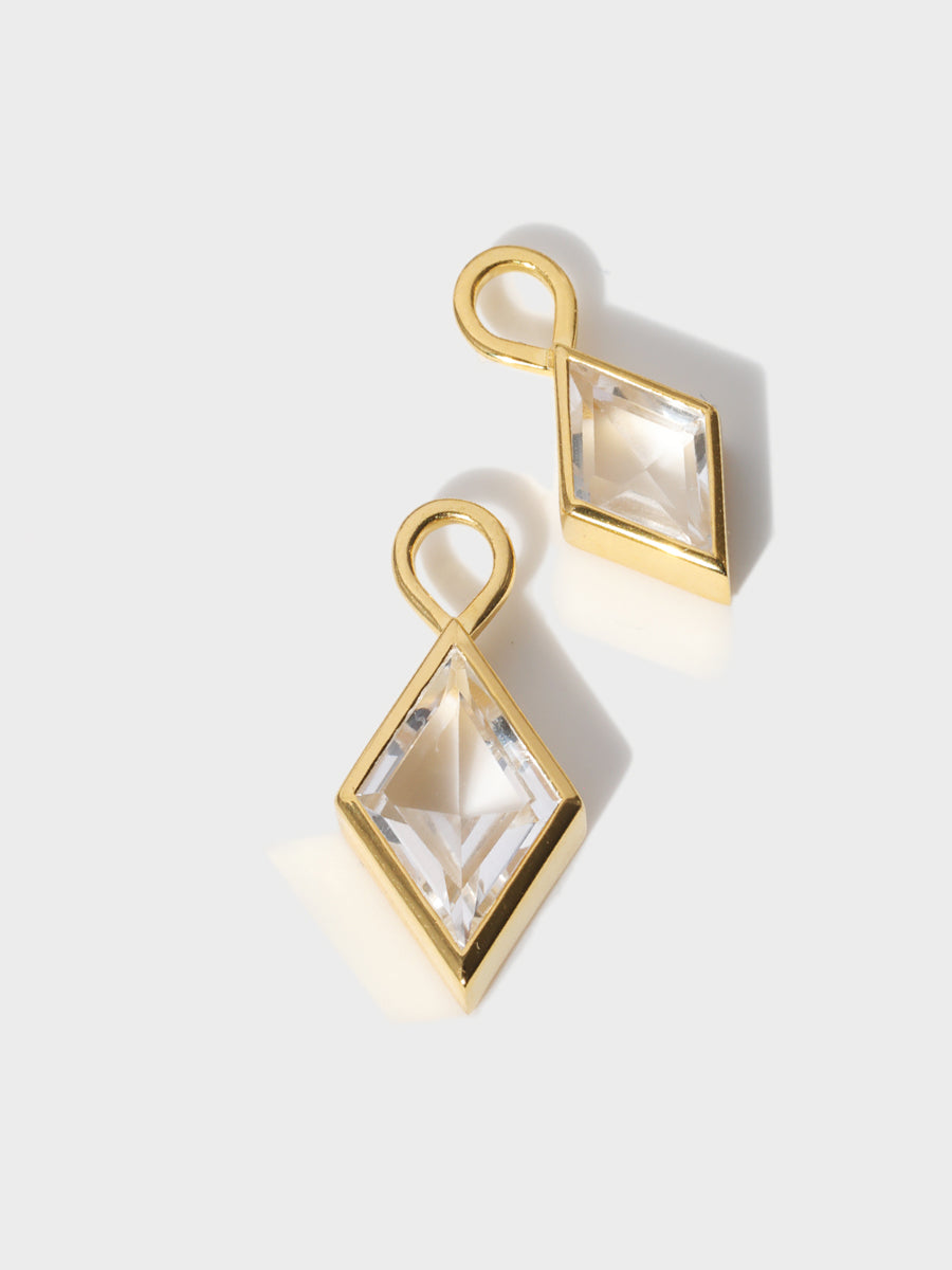 A large and small crystal diamond shaped charm set in gold casings with large connection hoops at the top. Grey backgrounds with shadow