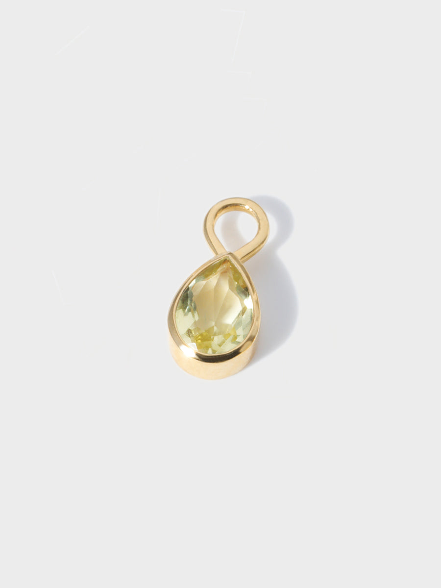 A large lemon topaz teardrop shaped charm set in a gold casing with large connection hoop at the top. Grey background with shadow
