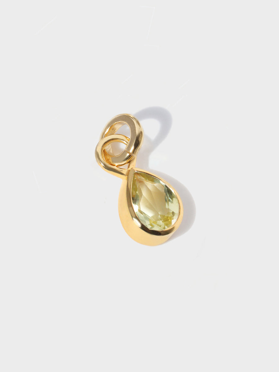 A large lemon topaz teardrop shaped charm set in a gold casing with large connection hoop at the top and clicker connector attahced. Grey background with shadow
