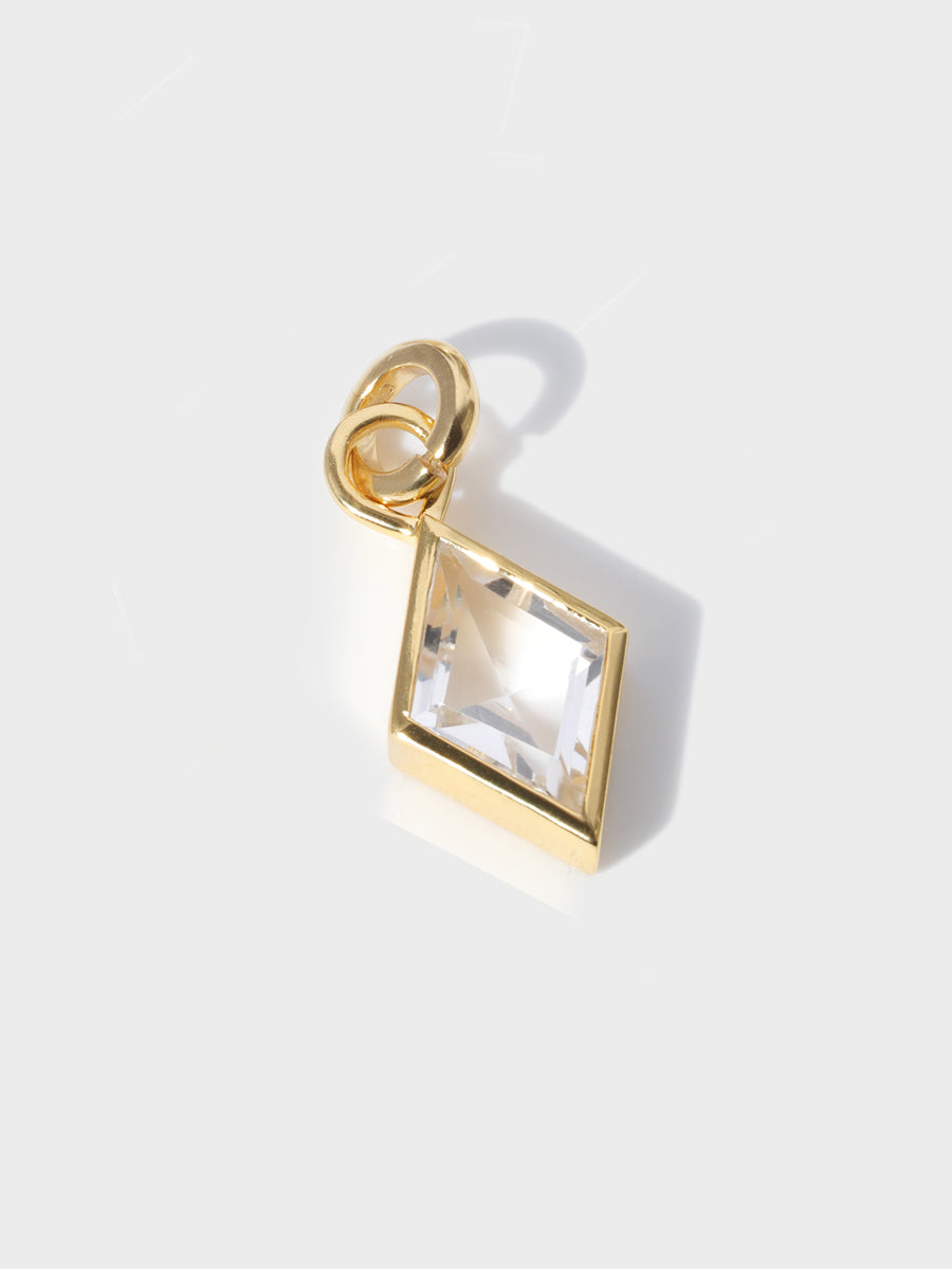 A large diamond shaped baguette shaped charm set in a gold casing with large connection hoop at the top with clicker connector attached. Grey background with shadow
