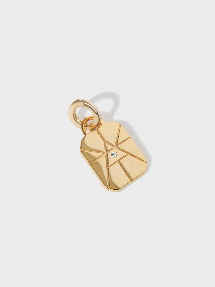 A gold air element rectangular charm with chamfered corners and a central blue topaz and large connection hoop at the top and clicker connector attached. Grey background with shadow