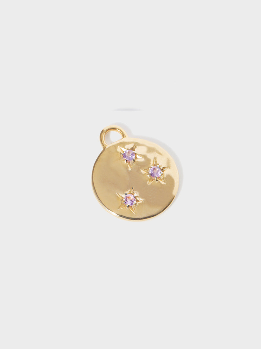A gold circular necklace pendant set with 3 Brazilian amethyst gemstones in star cutouts with a large hoop at the top. Grey background with shadow.