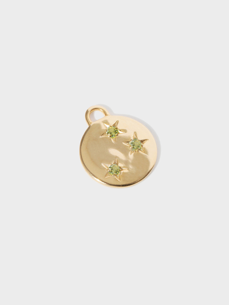 A gold circular necklace pendant set with 3 peridot gemstones in star cutouts with a large hoop at the top. Grey background with shadow.