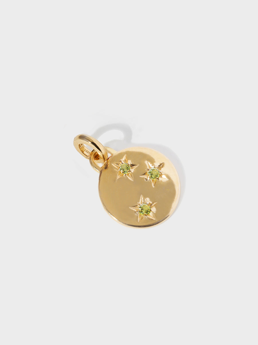 A gold circular necklace pendant set with 3 peridot gemstones in star cutouts with a large hoop at the top and clicker connector attached. Grey background with shadow.