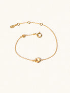 Delicate gold bracelet with two yellow citrine gemstones. One larger central 5mm gemstone and one smaller 2mm gemstone towards the round spring fastening. Set on a cream background with slight shadow.