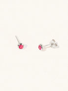 A pair of sterling silver small stud earrings with a 3mm ruby quartz gemstone in a 4mm setting and butterfly fastening. Set on a cream background with gentle shadowing.