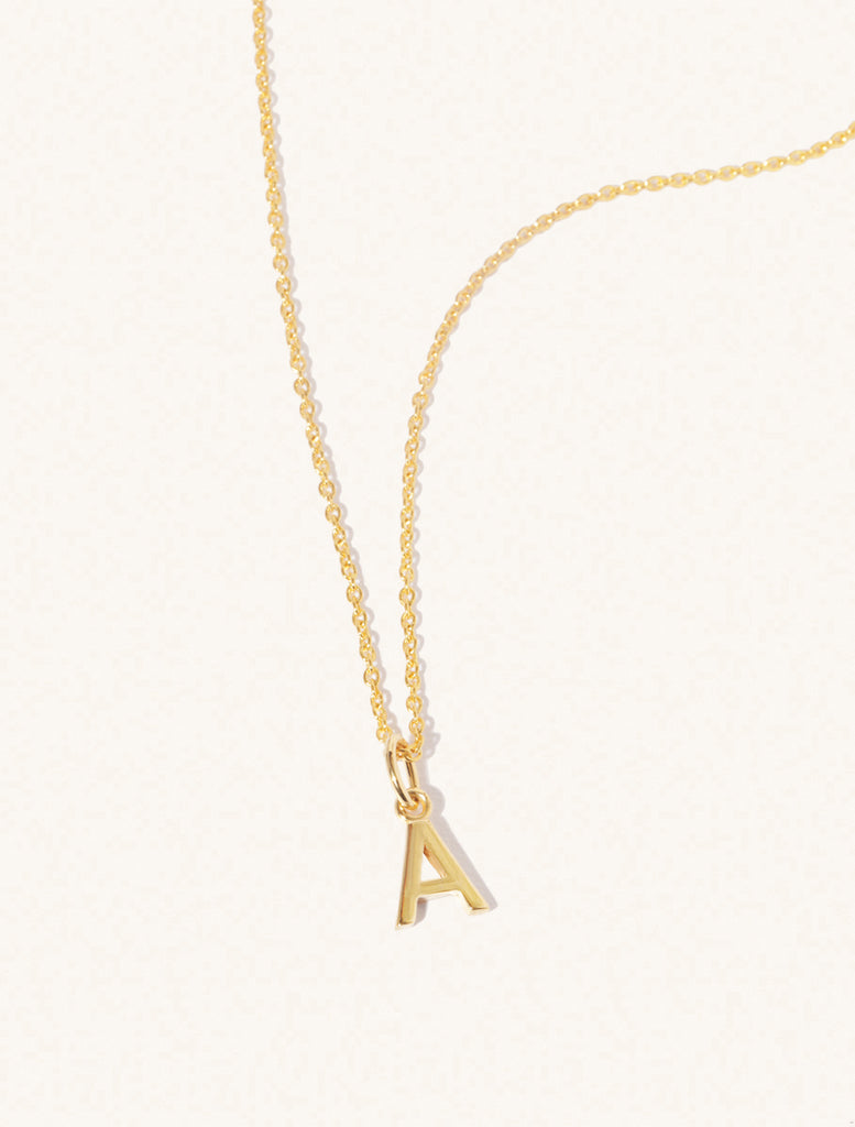 A gold chain necklace with the caplital letter A approximately 8mm x 6mm. Set on a cream background with gentle shadowing.