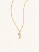 A gold chain necklace with the caplital letter I approximately 8mm x 6mm. Set on a cream background with gentle shadowing.