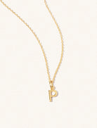 A gold chain necklace with the caplital letter P approximately 8mm x 6mm. Set on a cream background with gentle shadowing.