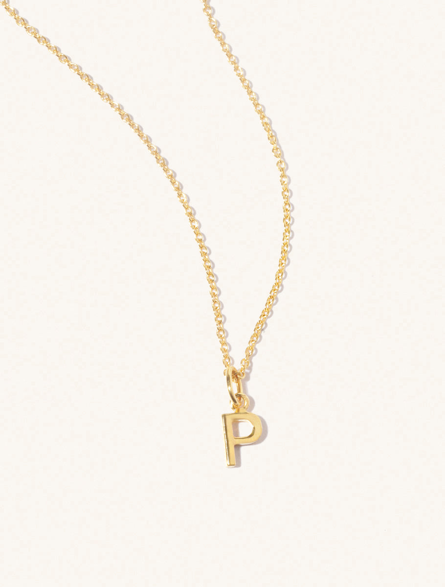 A gold chain necklace with the caplital letter P approximately 8mm x 6mm. Set on a cream background with gentle shadowing.