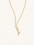 A gold chain necklace with the caplital letter Y approximately 8mm x 6mm. Set on a cream background with gentle shadowing.