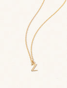 A gold chain necklace with the caplital letter Z approximately 8mm x 6mm. Set on a cream background with gentle shadowing.