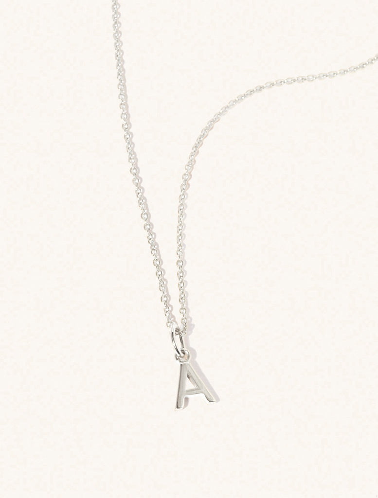 A sterling silver chain necklace with the caplital letter A approximately 8mm x 6mm. Set on a cream background with gentle shadowing.