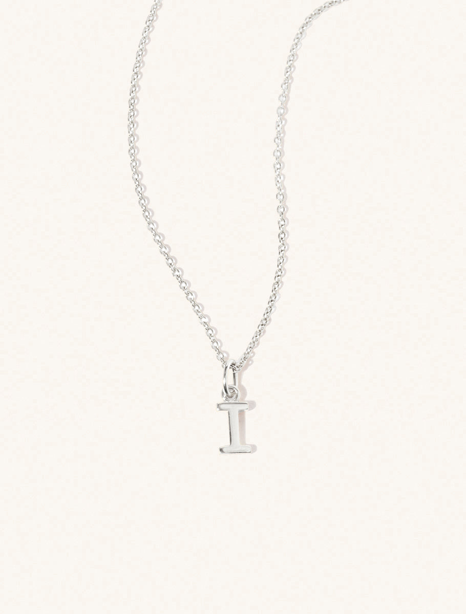 A sterling silver chain necklace with the caplital letter I approximately 8mm x 6mm. Set on a cream background with gentle shadowing.