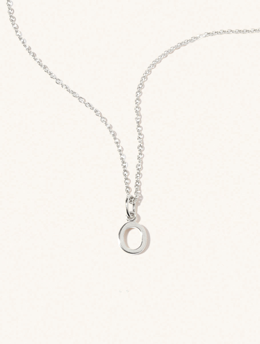 A sterling silver chain necklace with the caplital letter O approximately 8mm x 6mm. Set on a cream background with gentle shadowing.