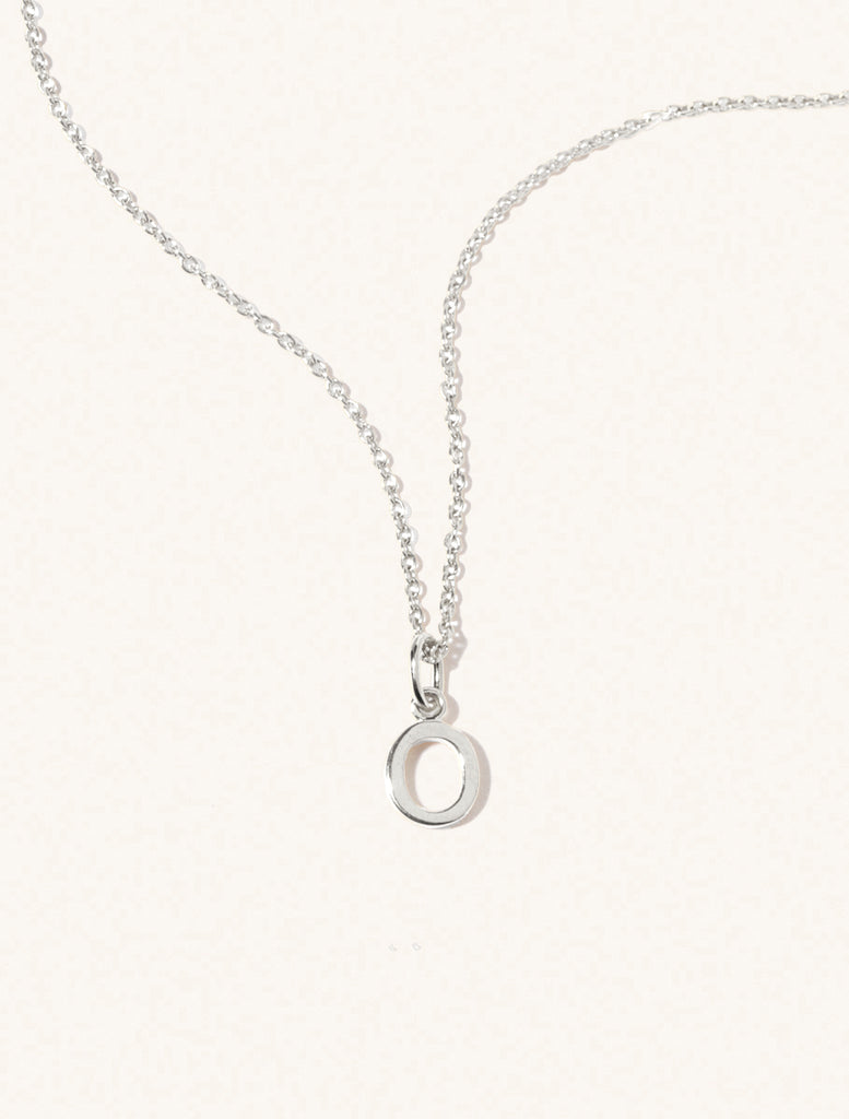 A sterling silver chain necklace with the caplital letter O approximately 8mm x 6mm. Set on a cream background with gentle shadowing.