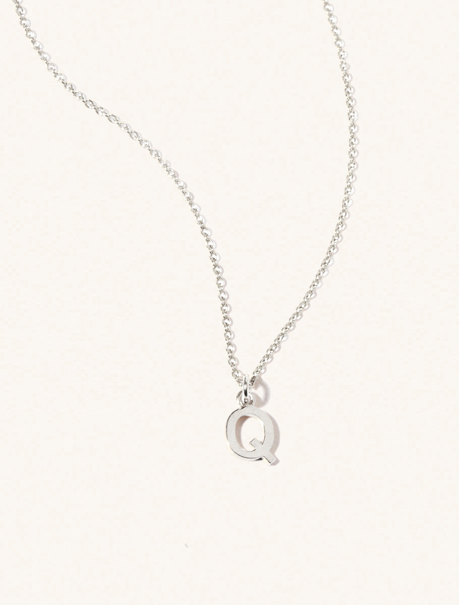 A sterling silver chain necklace with the caplital letter Q approximately 8mm x 6mm. Set on a cream background with gentle shadowing.