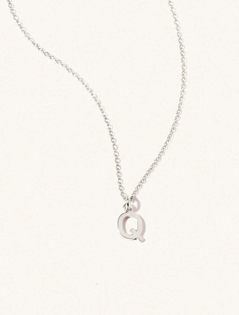 A sterling silver chain necklace with the caplital letter Q approximately 8mm x 6mm. Set on a cream background with gentle shadowing.