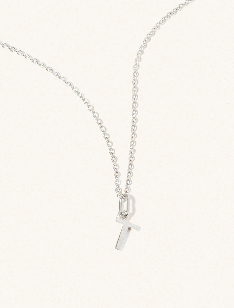 A sterling silver chain necklace with the caplital letter T approximately 8mm x 6mm. Set on a cream background with gentle shadowing.