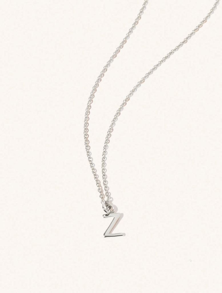 A sterling silver chain necklace with the caplital letter Z approximately 8mm x 6mm. Set on a cream background with gentle shadowing.