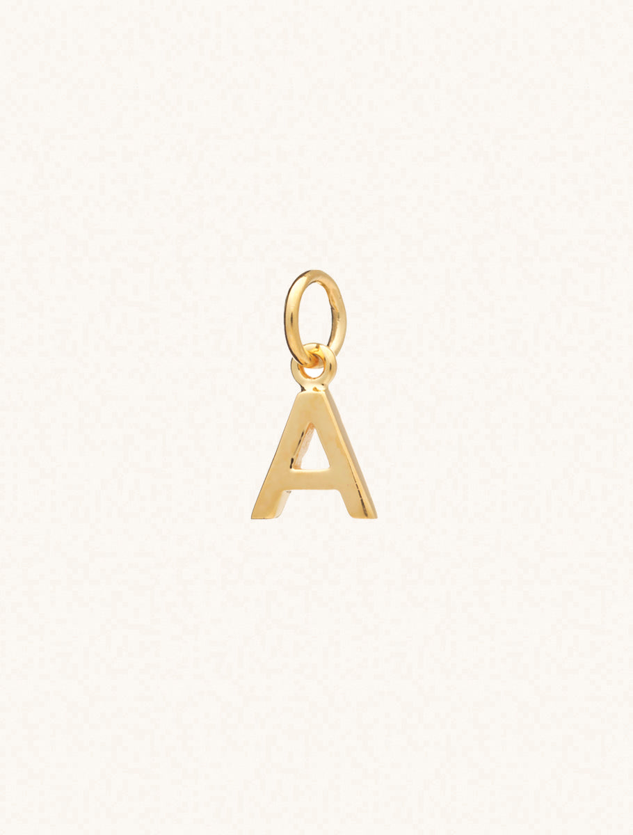 A gold caplital letter A approximately 8mm x 6mm with a connecting ring to thread through a necklace at the top. Set on a cream background.