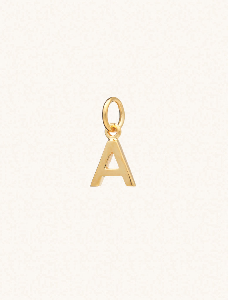 A gold caplital letter A approximately 8mm x 6mm with a connecting ring to thread through a necklace at the top. Set on a cream background.