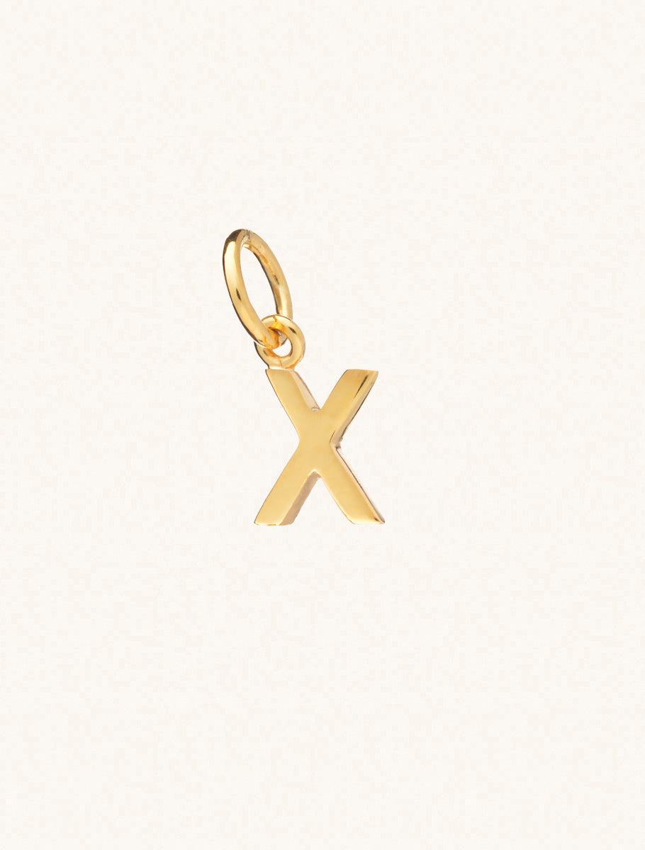 A gold caplital letter X approximately 8mm x 6mm with a connecting ring to thread through a necklace at the top. Set on a cream background.