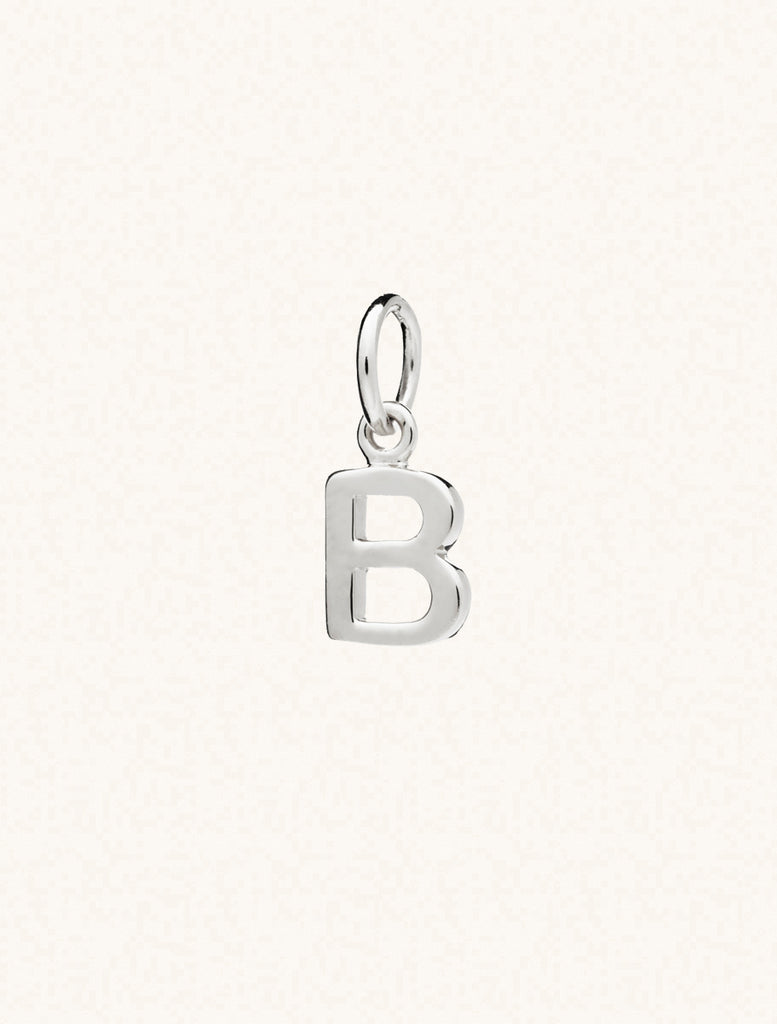 A sterling silver caplital letter B approximately 8mm x 6mm with a connecting ring to thread through a necklace at the top. Set on a cream background.