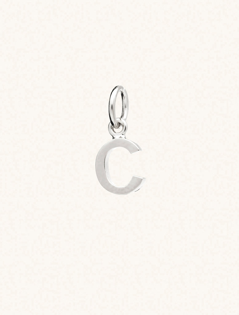 A sterling silver caplital letter C approximately 8mm x 6mm with a connecting ring to thread through a necklace at the top. Set on a cream background.