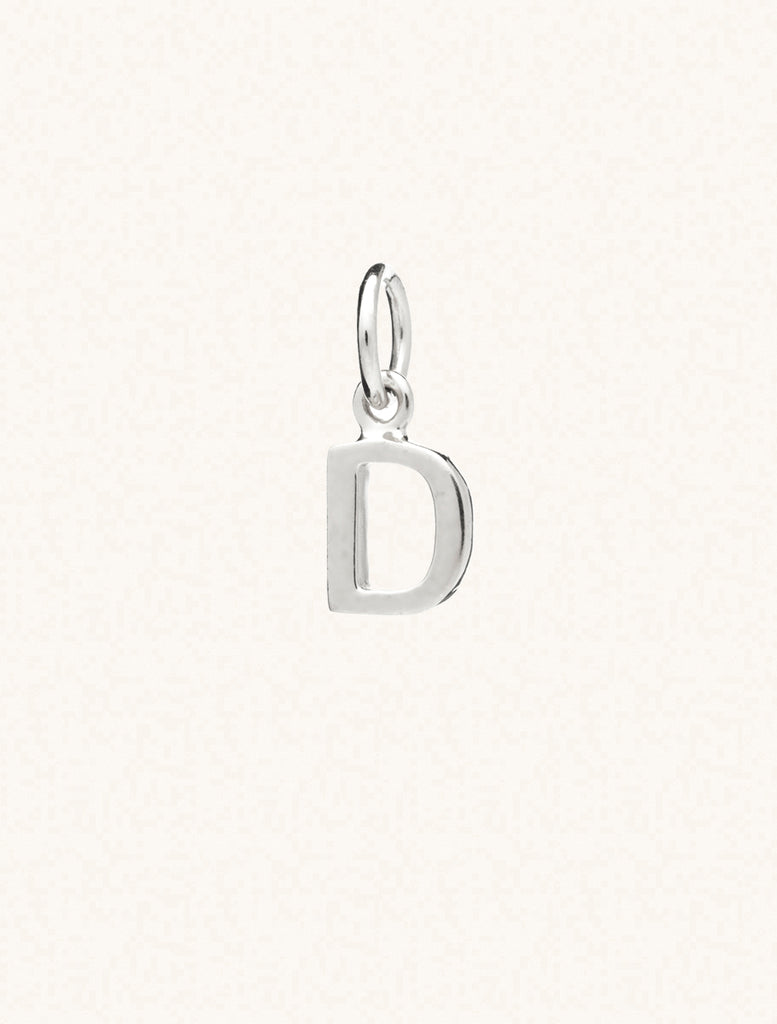 A sterling silver caplital letter D approximately 8mm x 6mm with a connecting ring to thread through a necklace at the top. Set on a cream background.