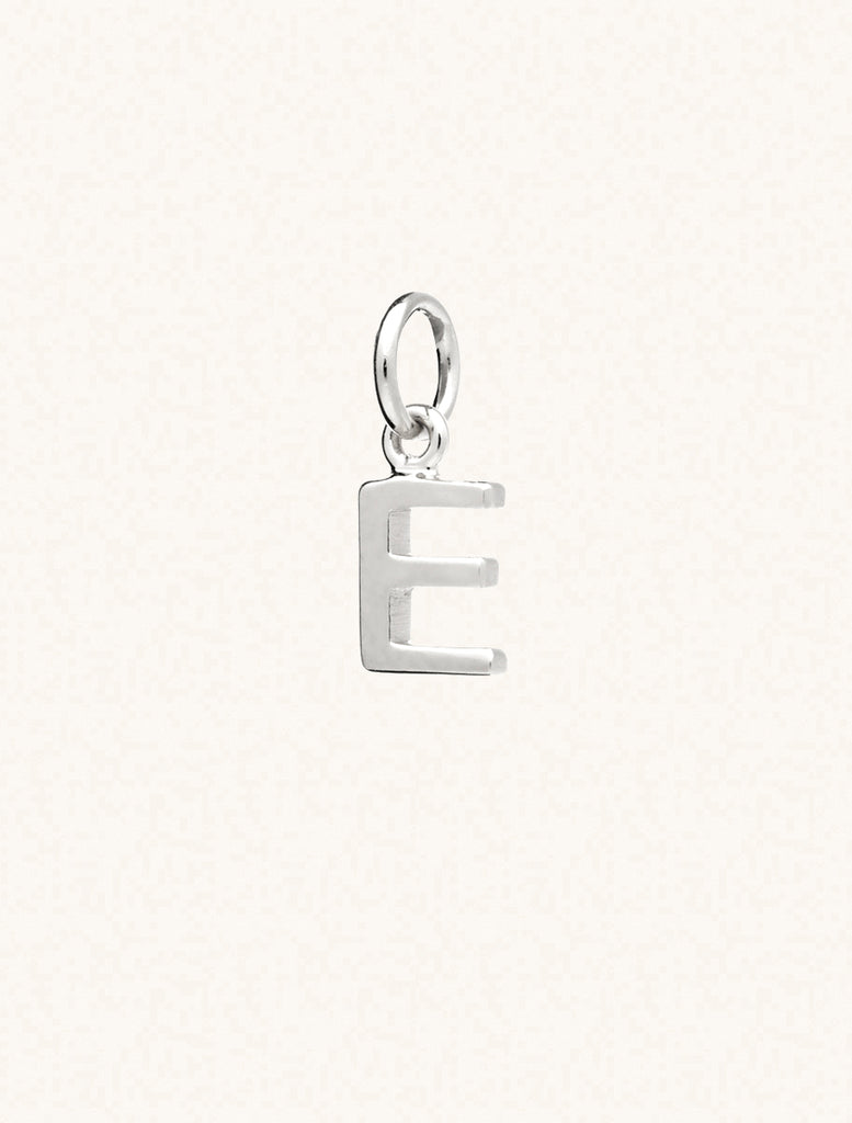 A sterling silver caplital letter E approximately 8mm x 6mm with a connecting ring to thread through a necklace at the top. Set on a cream background.