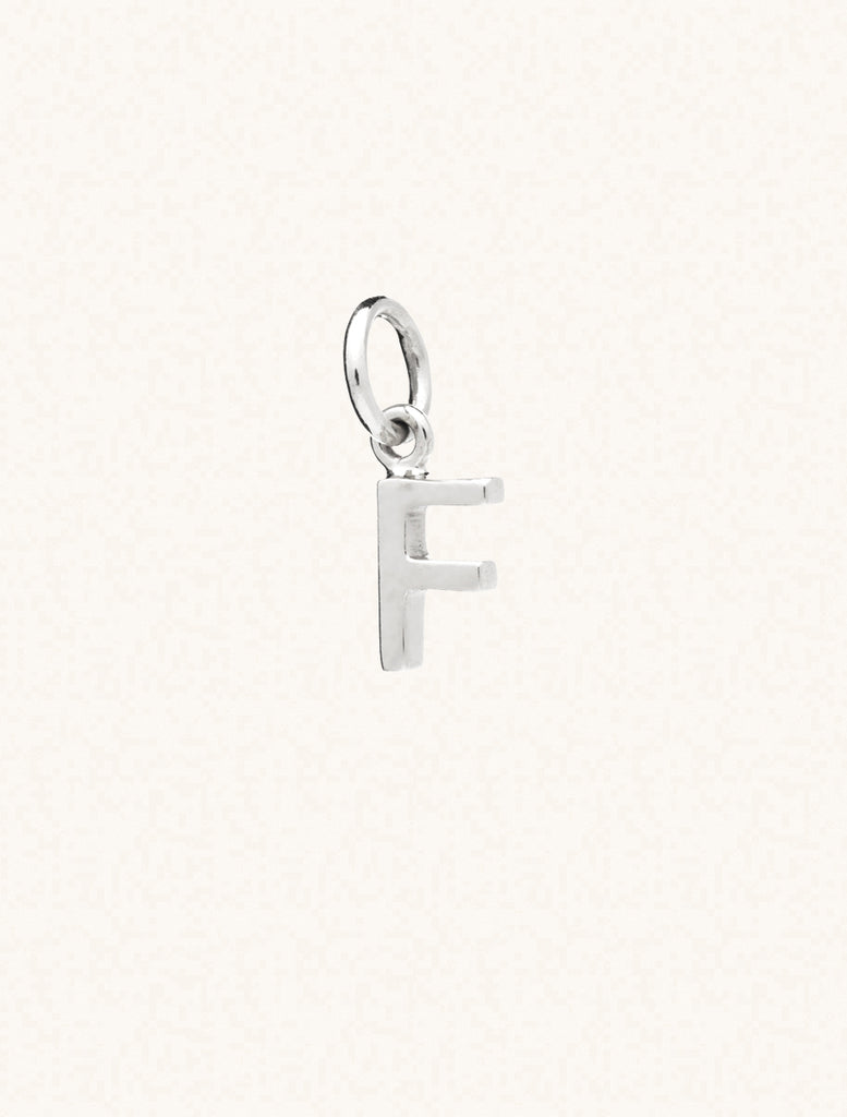 A sterling silver caplital letter F approximately 8mm x 6mm with a connecting ring to thread through a necklace at the top. Set on a cream background.