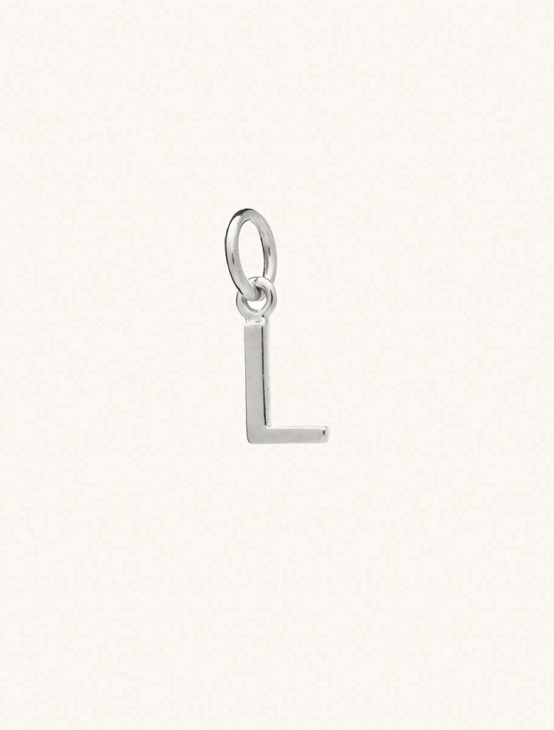 A sterling silver caplital letter L approximately 8mm x 6mm with a connecting ring to thread through a necklace at the top. Set on a cream background.