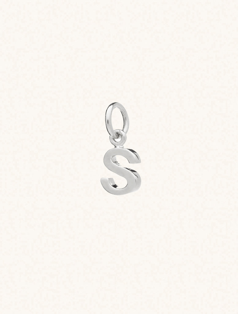 A sterling silver caplital letter S approximately 8mm x 6mm with a connecting ring to thread through a necklace at the top. Set on a cream background.