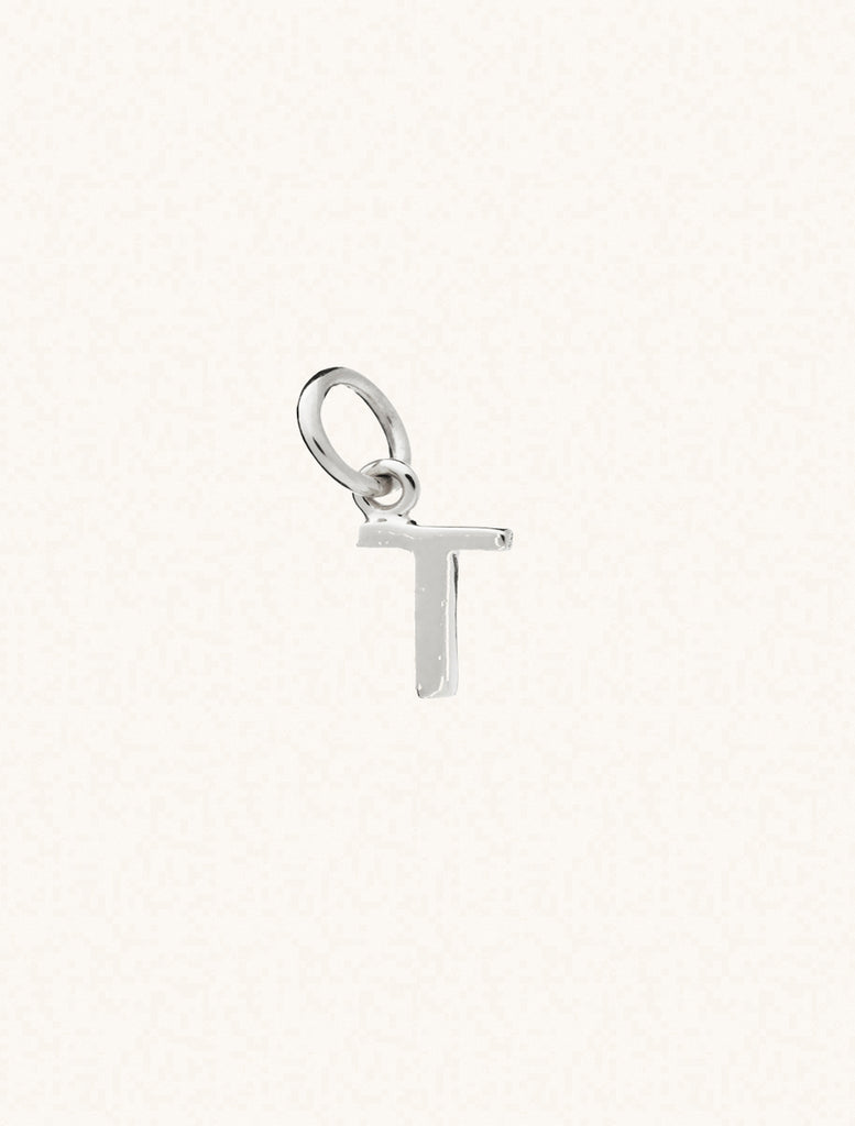 A sterling silver caplital letter T approximately 8mm x 6mm with a connecting ring to thread through a necklace at the top. Set on a cream background.