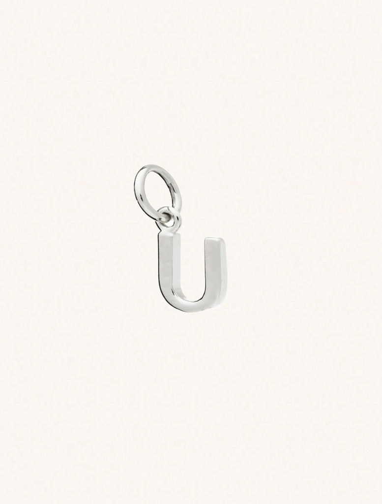 A sterling silver caplital letter U approximately 8mm x 6mm with a connecting ring to thread through a necklace at the top. Set on a cream background.