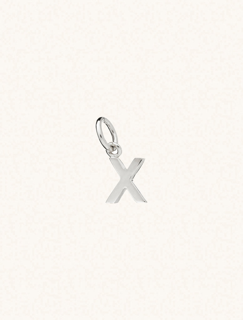 A sterling silver caplital letter X approximately 8mm x 6mm with a connecting ring to thread through a necklace at the top. Set on a cream background.