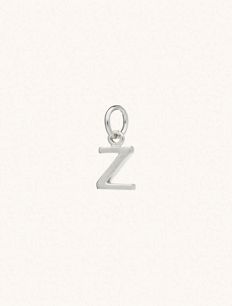 A sterling silver caplital letter Z approximately 8mm x 6mm with a connecting ring to thread through a necklace at the top. Set on a cream background.