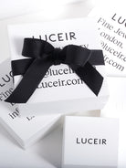 Four Luceir logo'd white boxes randomly place with a black ribbon tied around the central box