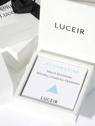 Luceir white packaging card set in a box saying Aquamarine, March Birthstone, Serenity, Creativity, Optimism followed by a baby blue triangle symbol underneath with Luceir logo at the bottom